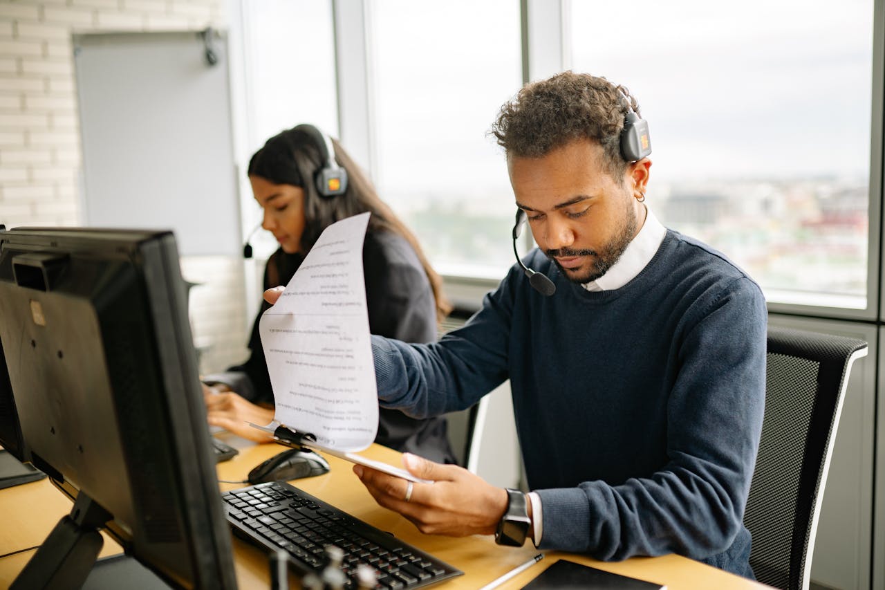 our-services-1 Call center agents with headsets working in a modern office setting, reviewing documents.